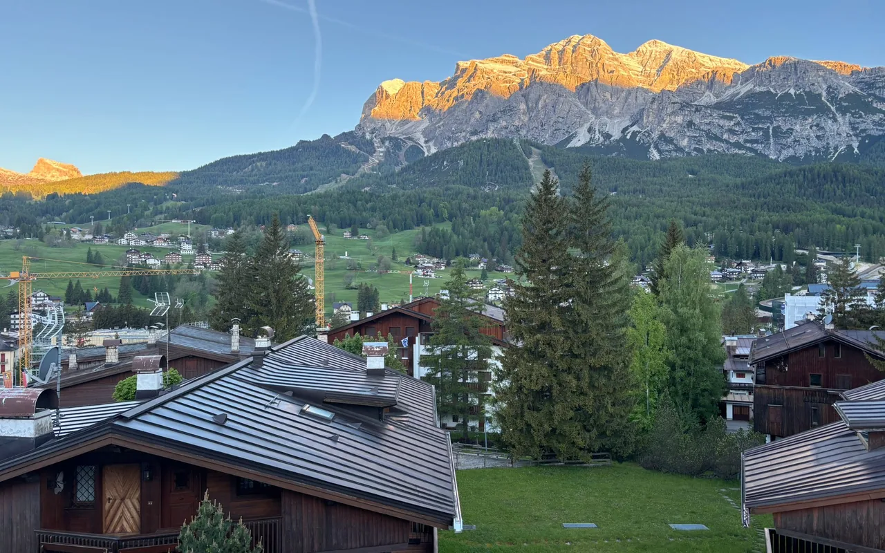 Le Dolomiti accese dal tramonto sopra i tetti e i boschi di Cortina