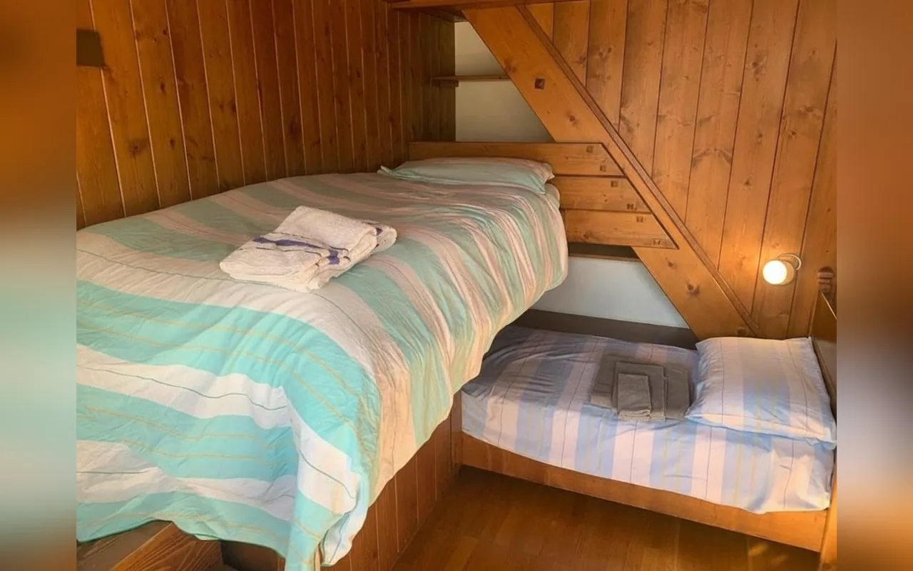 Camera mansardata con letti singoli e soffitto in legno