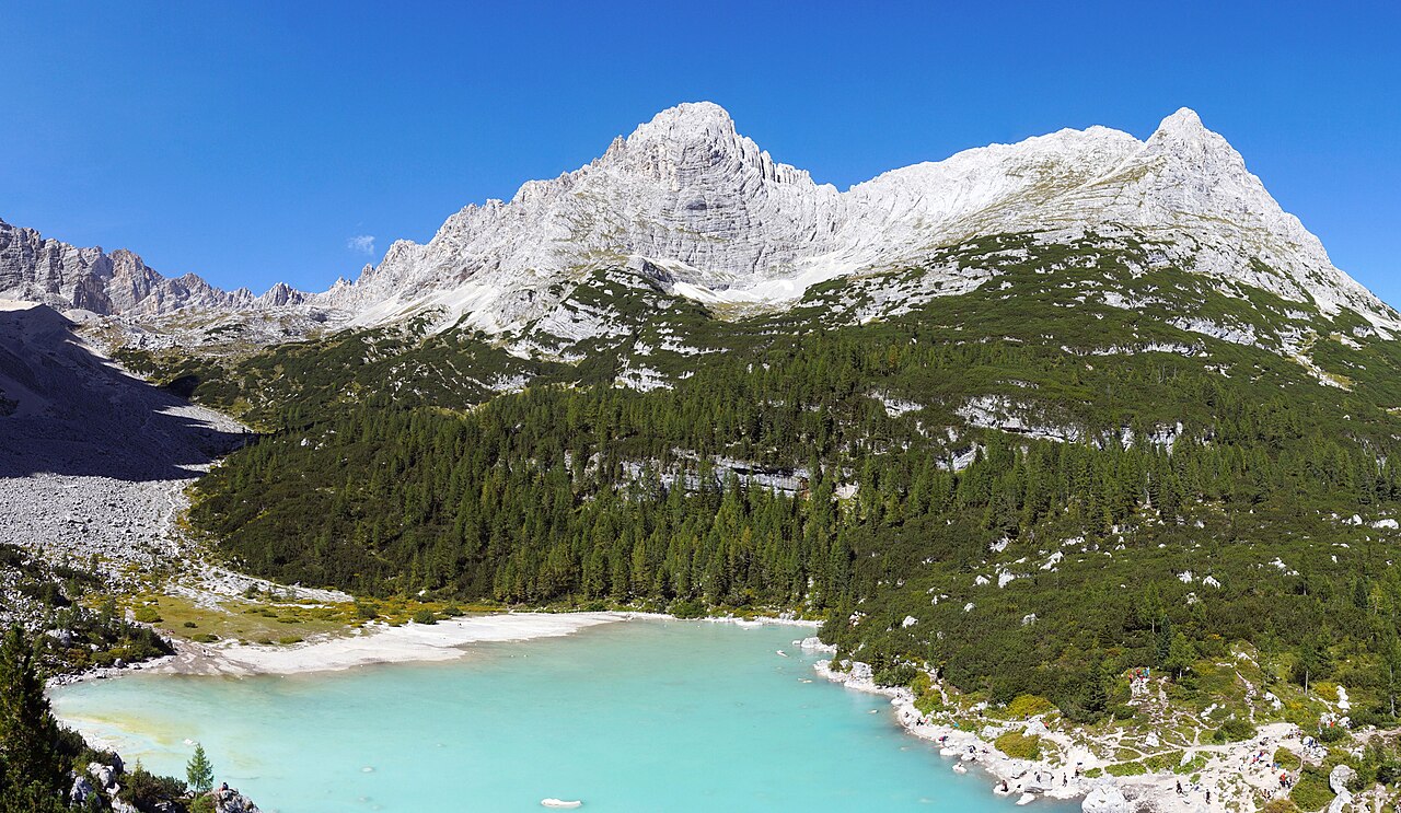 Il lago di Sorapis con l'acqua azzurro chiaro, il bosco sulle rive e la cima della Cesta sullo sfondo