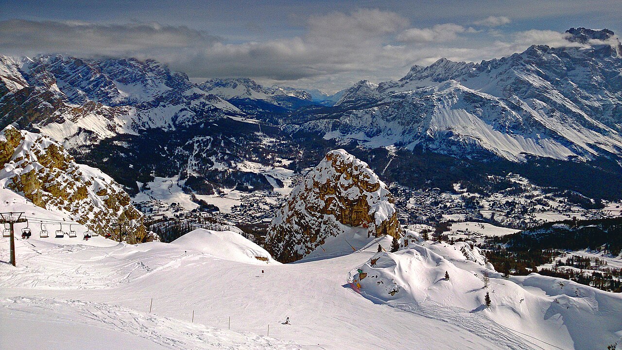 Pista innevata con seggiovia sul versante delle Tofane, con la conca di Cortina d'Ampezzo e le montagne sullo sfondo