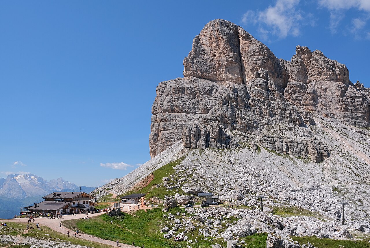 Il rifugio Averau con la sua terrazza ai piedi della grande parete rocciosa dell'Averau, con cime innevate sullo sfondo